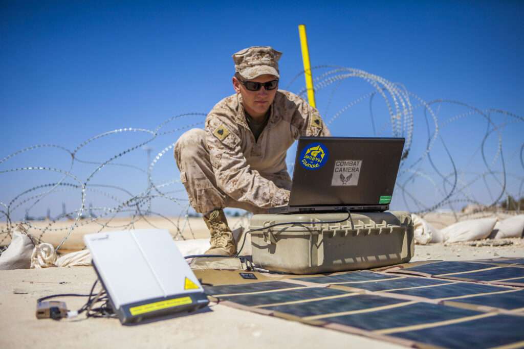 US Marine Sargent 26th Marine Expeditionary Unit (MEU) combat cameraman, transmits imagery using a Broadband Global Area Network (BGAN) powered by a Solar Portable Alternative Communications Energy System (SPACES) kit from King Faisal Air Base in Jordan to the USS Kearsarge.