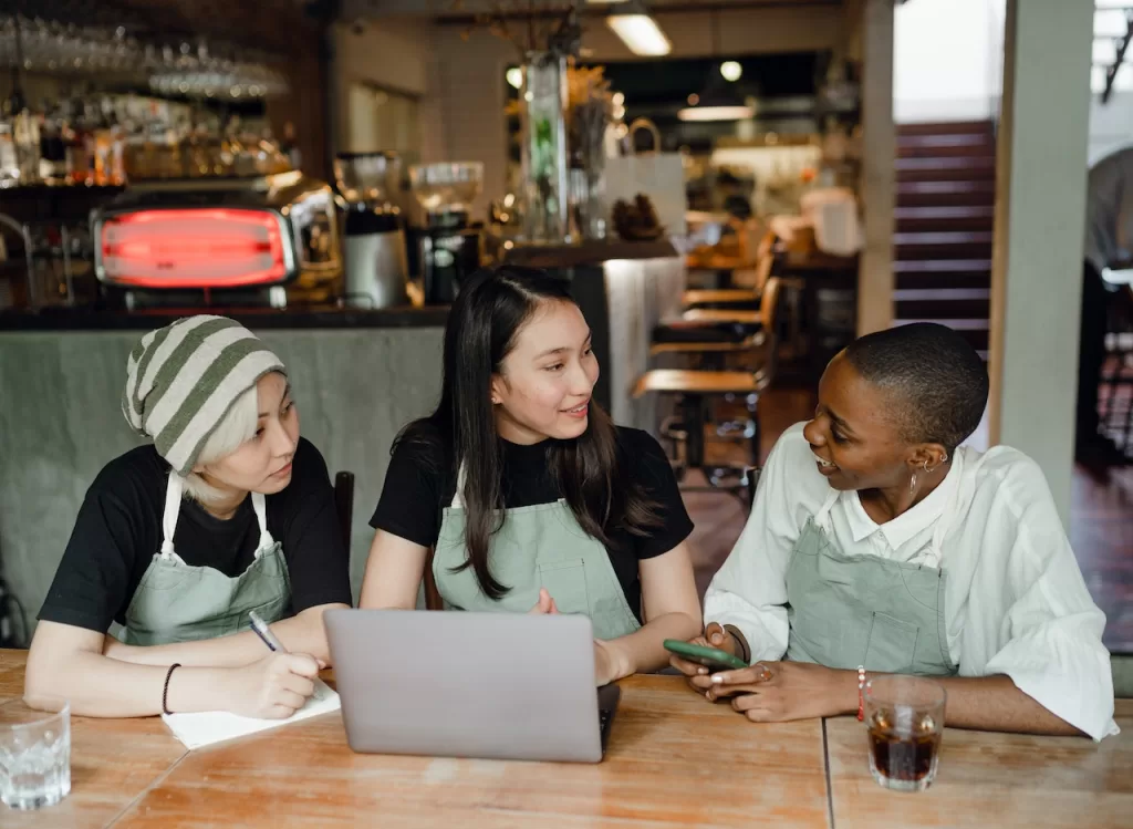 Three female entreprenuers reviewing bills for their coffee shop.