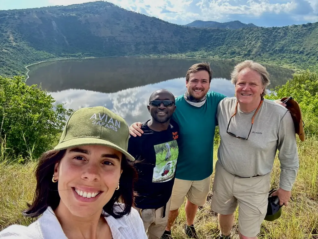 Crammy of Avian Safaris taking a selfie with Alexander Boom, Alexander's wife Lari, and his dad Henry in front a Crater Lake in Queen Elizabeth National Park.