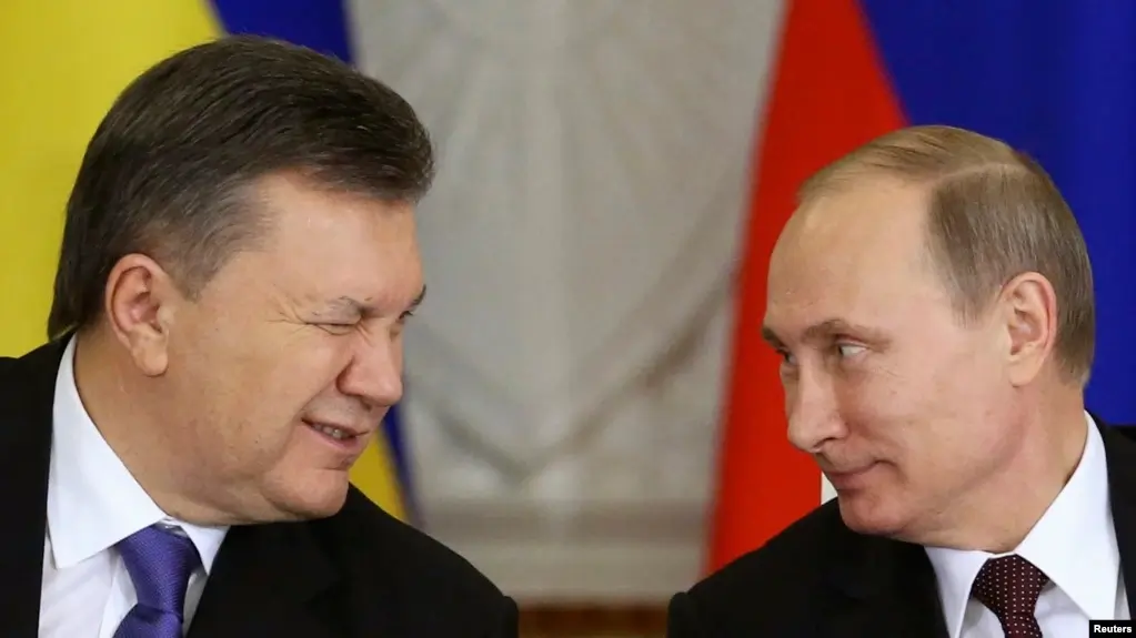 Ukraine's 4th president Victor Yanukovych sits next Russia's president Vladimir Putin and winks at him.