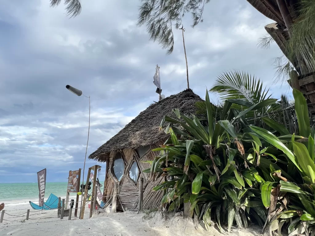 Small solar panel atop a thatched roof kite surfing school on the beach in Paje, Zanzibar, Tanzania.