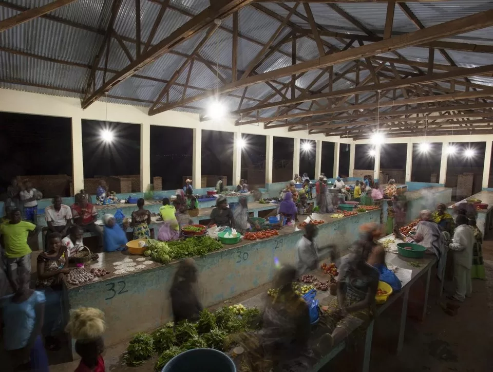 Busy night market in Msimba, Tanzania, illuminated with ceiling lights.